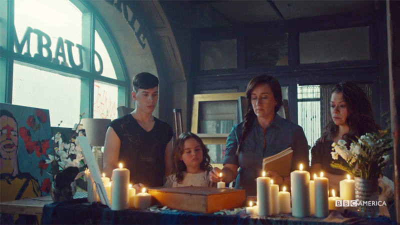 Mrs. S, Felix, Sarah and Kira stand around candles and MK's mask