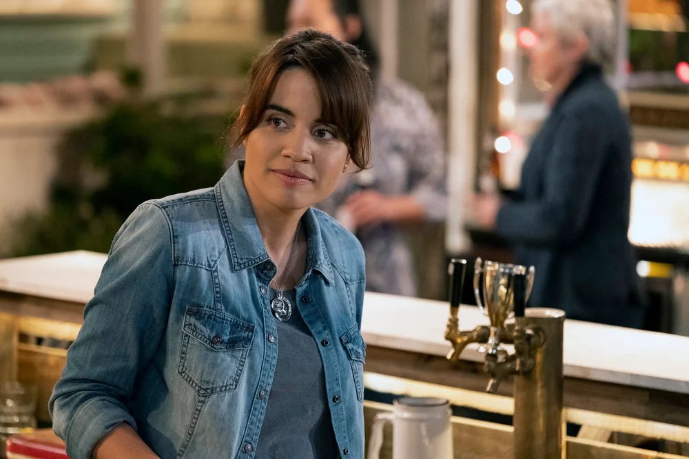 Natalie Morales as "Abby" in Abby's, bartending in her denim shirt