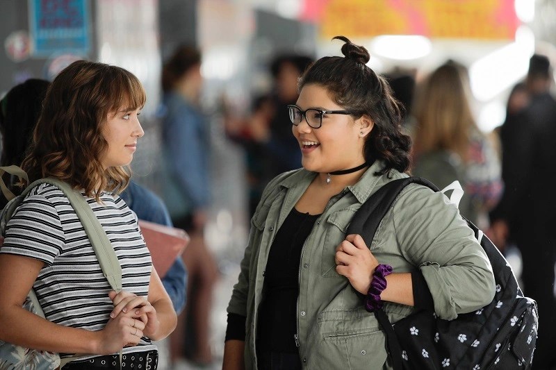 two teenagers being queer in a high school hallway