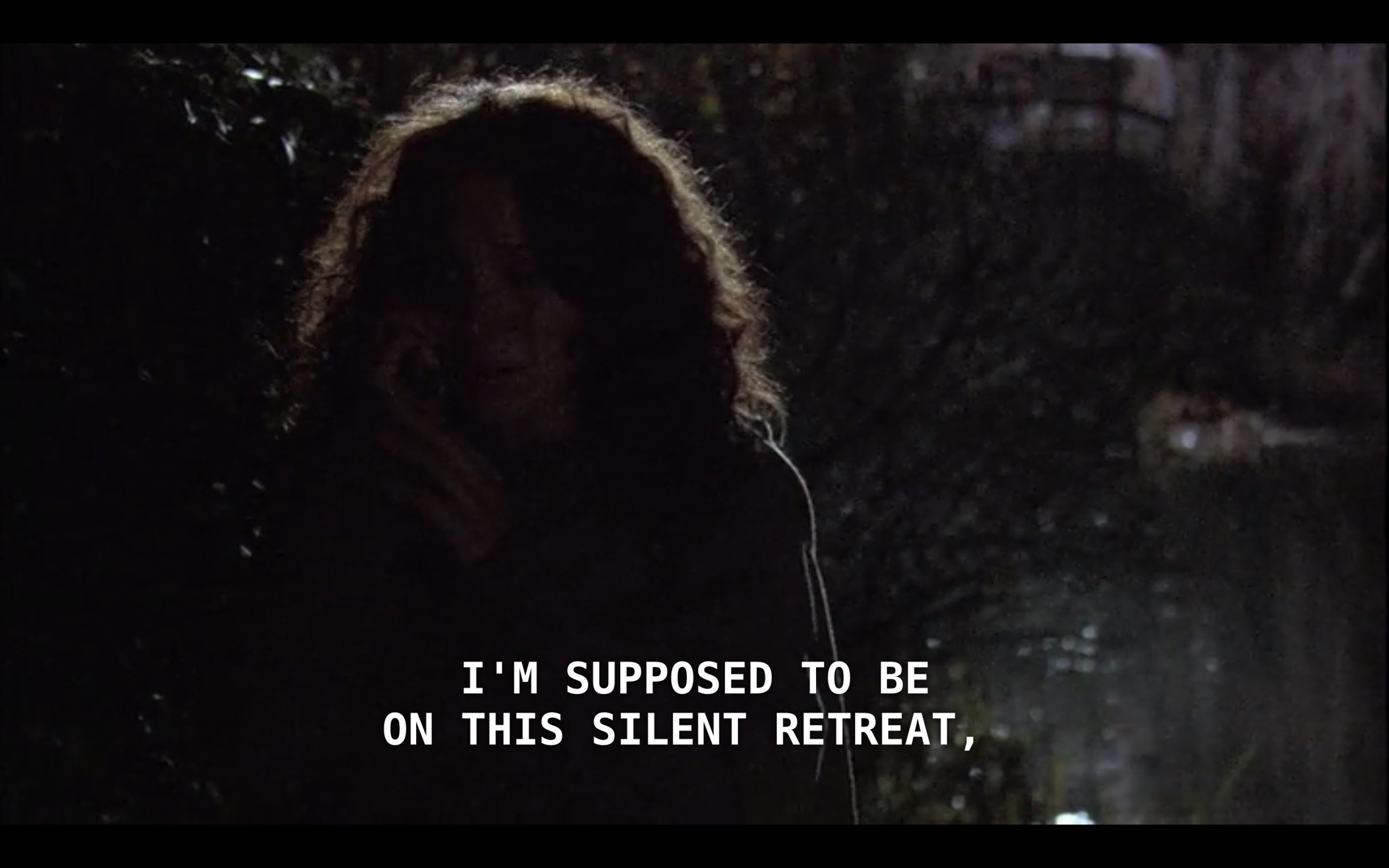 Bette is calling Tina on her cell phone in a dark forest at night. She says, "I'm supposed to be on this silent retreat."
