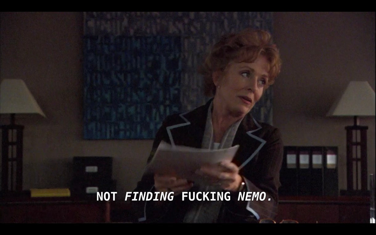 Peggy Peabody sits at the head of a conference table, holding a stack of papers and wearing a black blazer with blue trim. She says to Dylan's lawyer, "This is a documentary, not Finding fucking Nemo"