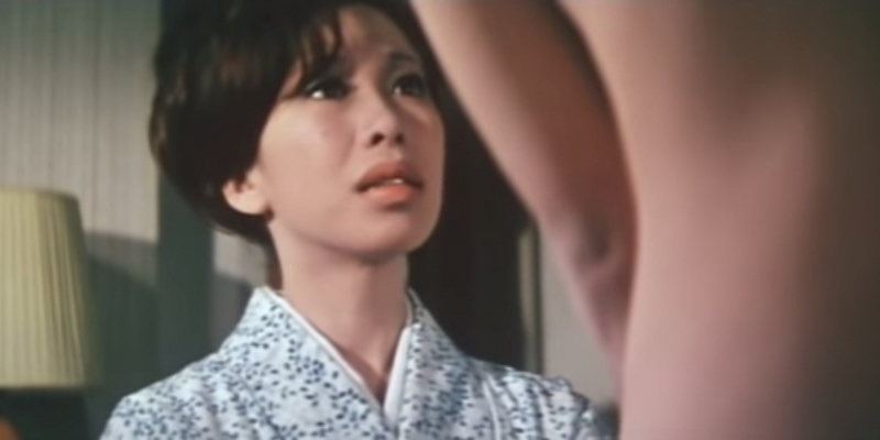 A still from Manji. A clothed woman looks up at a nude woman.
