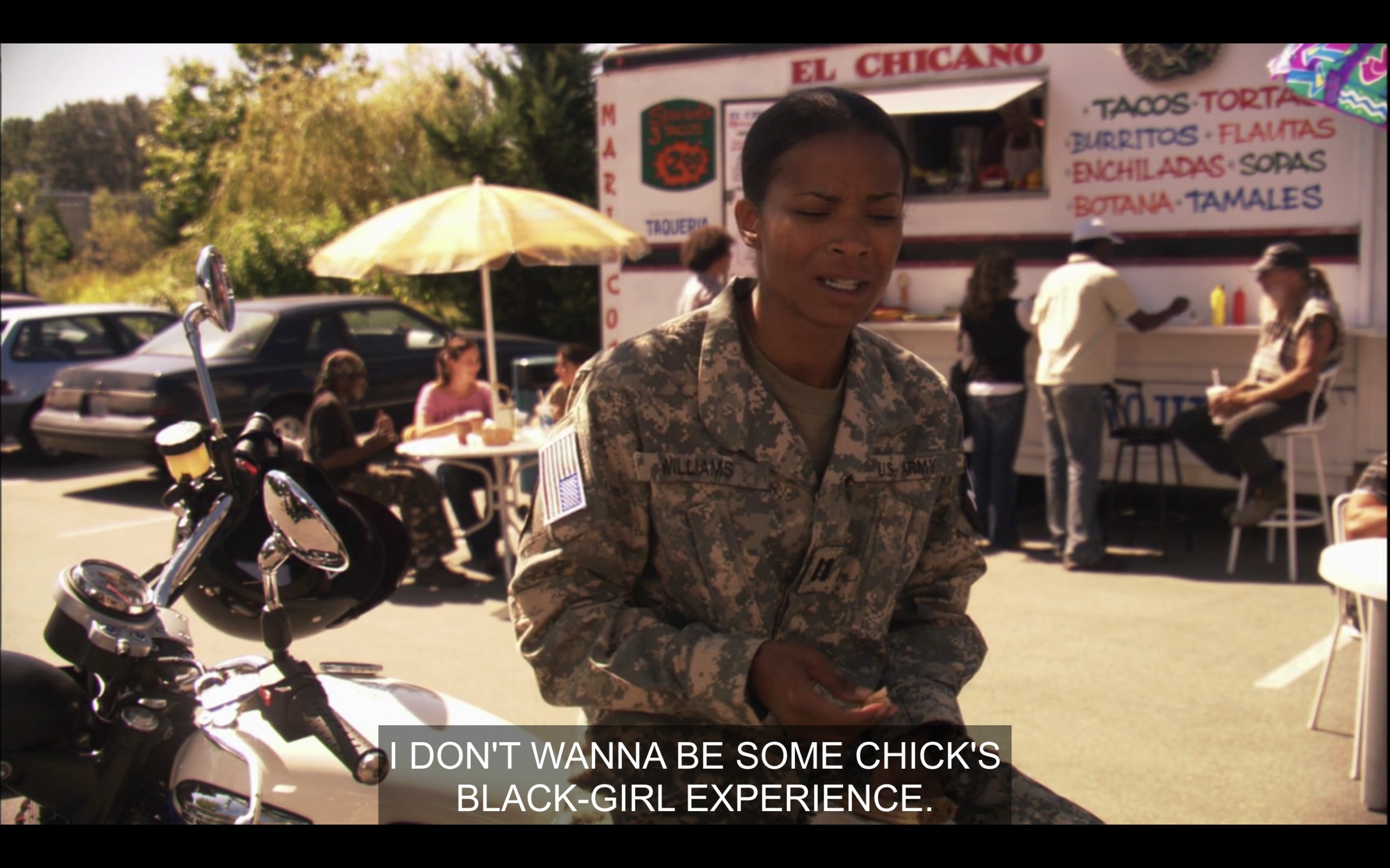 Tasha in full military uniform. Her bike is parked behind her. We're outside, it's sunny. There's a taco truck in the background. Tasha is talking to Papi saying "I don't want to be some chick's Black Girl Experience."