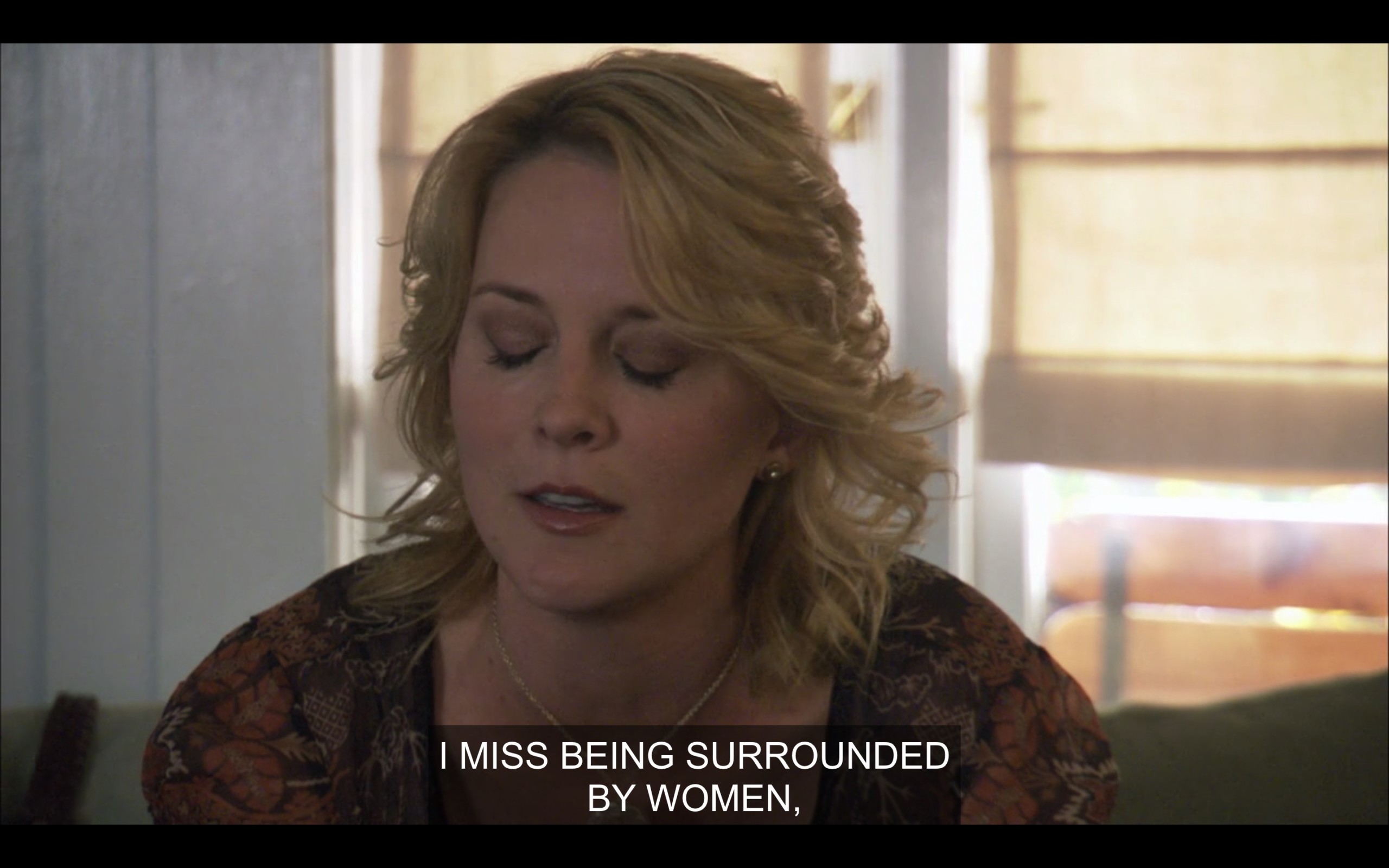 Tina sitting on a couch with her eyes closed. She says, "I miss being surrounded by women."