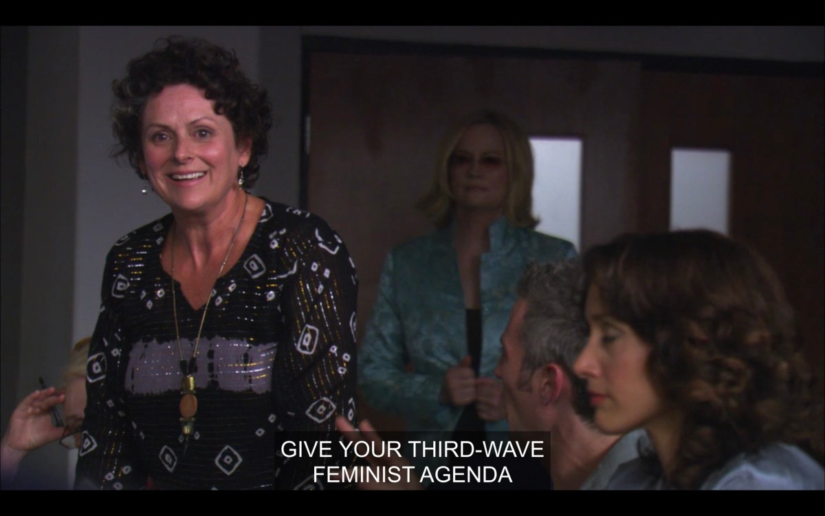 A woman with short curly brown hair, wearing a black patterned blouse and a long necklace, says, "Give your third-wave feminist agenda." Also in frame are Phyllis (in a teal jacket) and Bette.