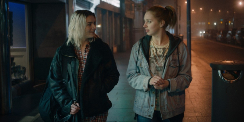 A still from the 44th best lesbian movie of all time A Date for Mad Mary. Two young women walk along a street at night.