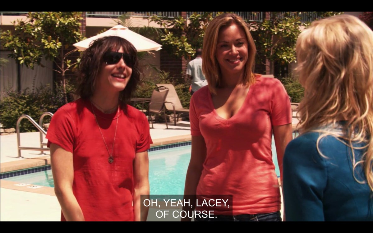 Shane and Paige are at an apartment complex standing in front of the pool. Shane is half-smiling and Paige is grimace-smiling as their realtor goes through all of Shane's exes.