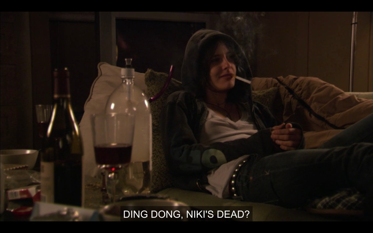 Shane in a hoodie on the sofa, very stoned, saying "Ding Dong, Niki's dead"