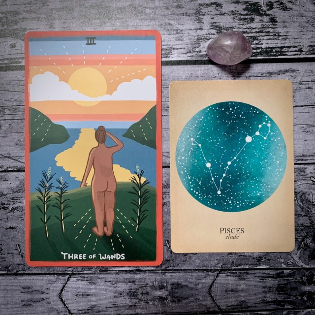 A photo of the tarot card for Three of Wands and the astrological card representing Pisces, along with a small crystal