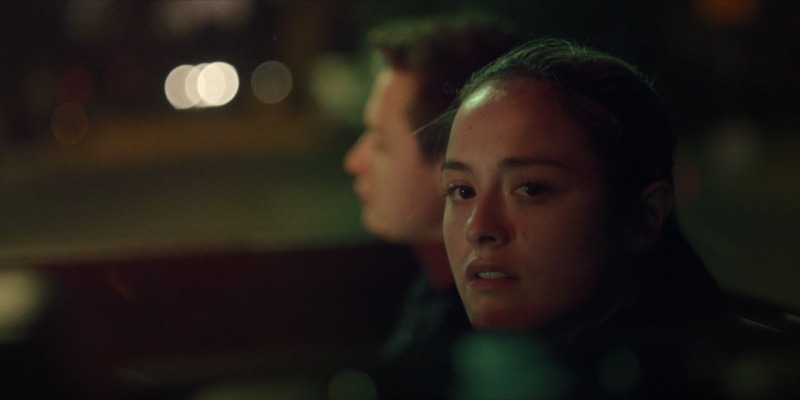 Deliah stares off into the camera from the bus at night during a school trip.