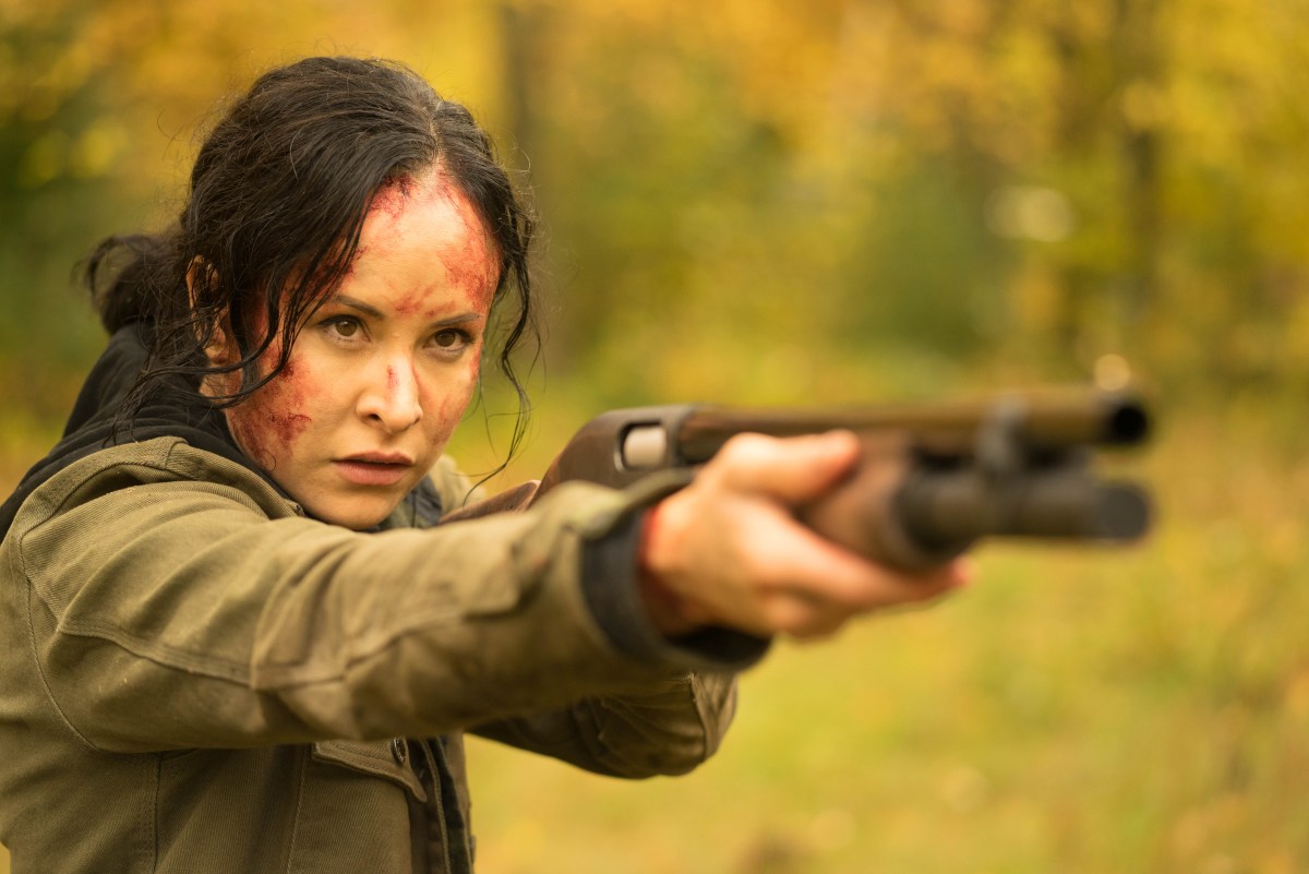 Renee with blood on her face points a shotgun