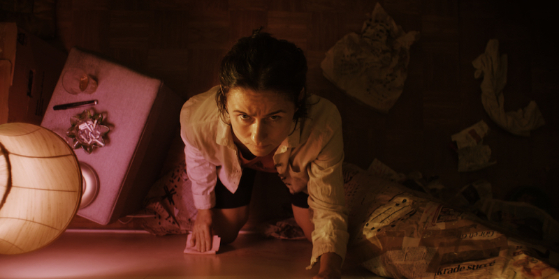 Shot from above a woman looks up pressed against a wall.