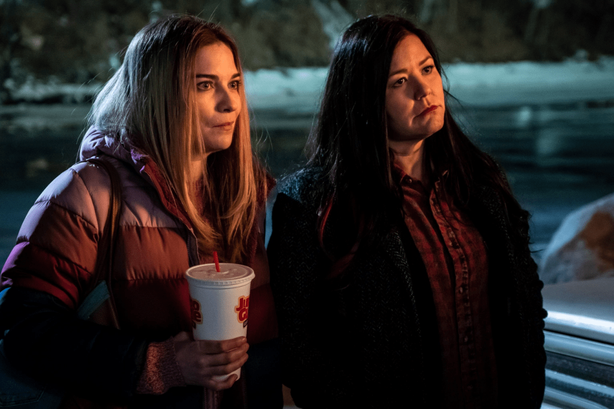 Allison and Patty stand in the dark holding takeout cups