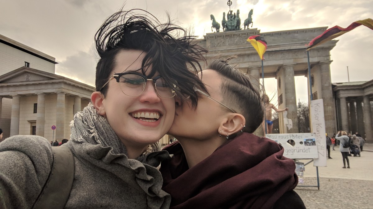 Sadie kisses Nico on the cheek in front of the Brandenburg Gate