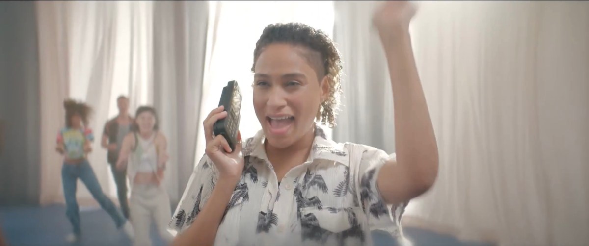 Sophie on a vintage cell phone doing a fist bump