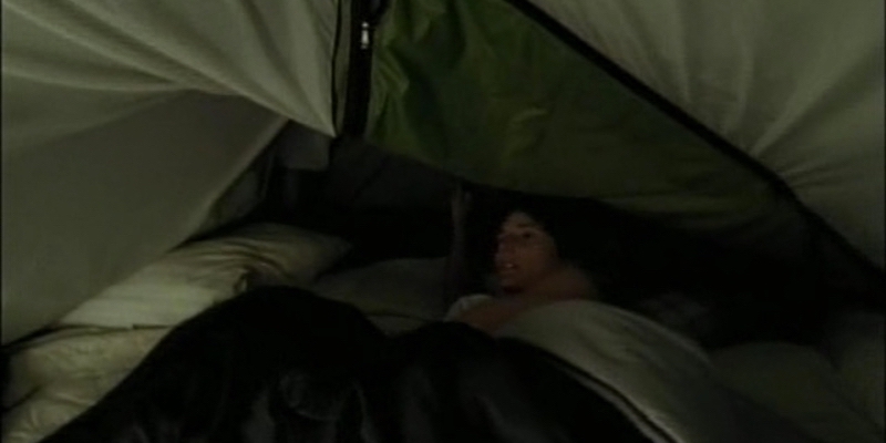 A woman looks up as her tent caves in.