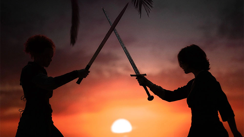 Kit and Jade sword fight in the sunset.
