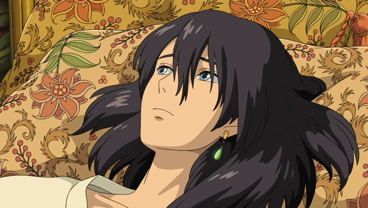 a screencap of howl lying depressively on a brocade pillow. he is an anime guy with dark hair and an earring