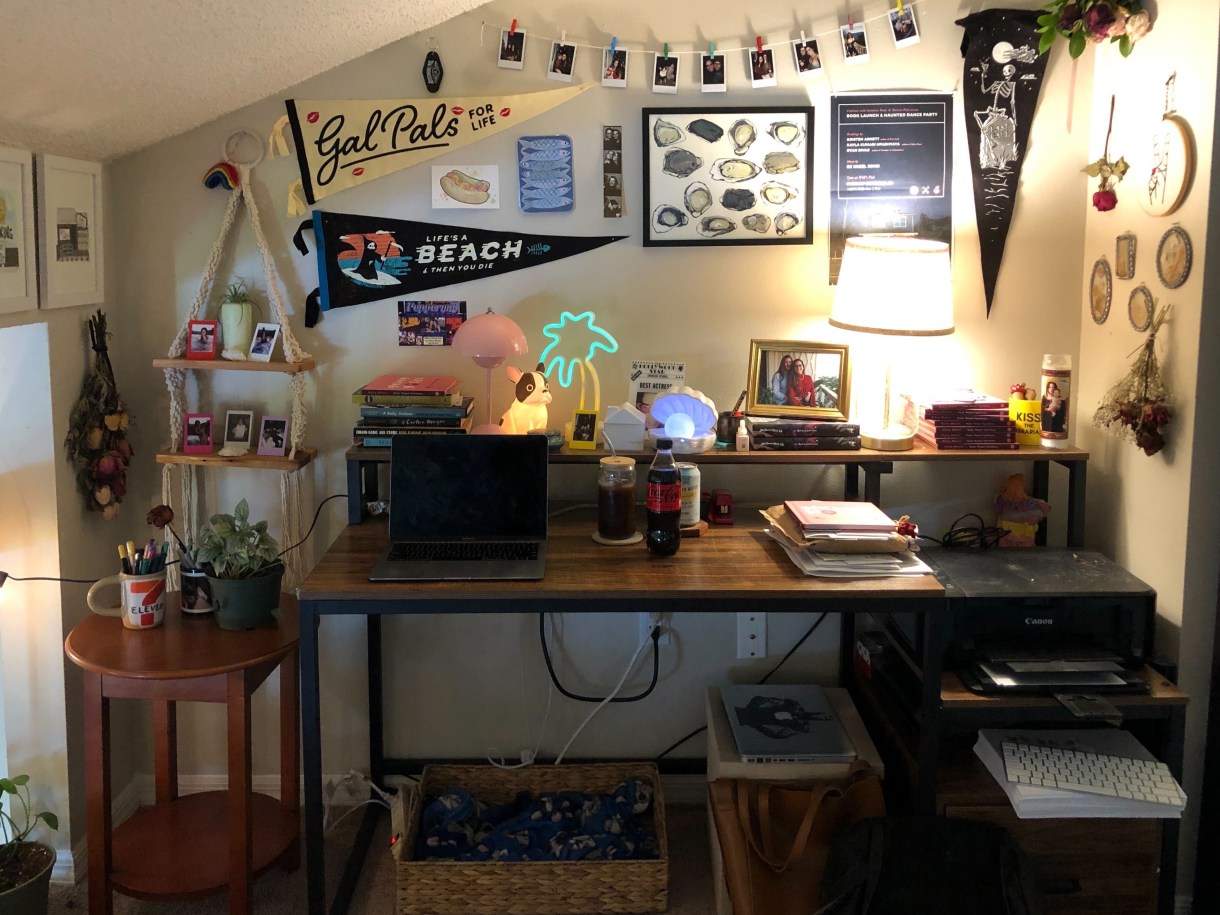 A photo of Kayla's office showing her desk, the art pinned to her walls, books, lamps and plants. It's cozy and organized.