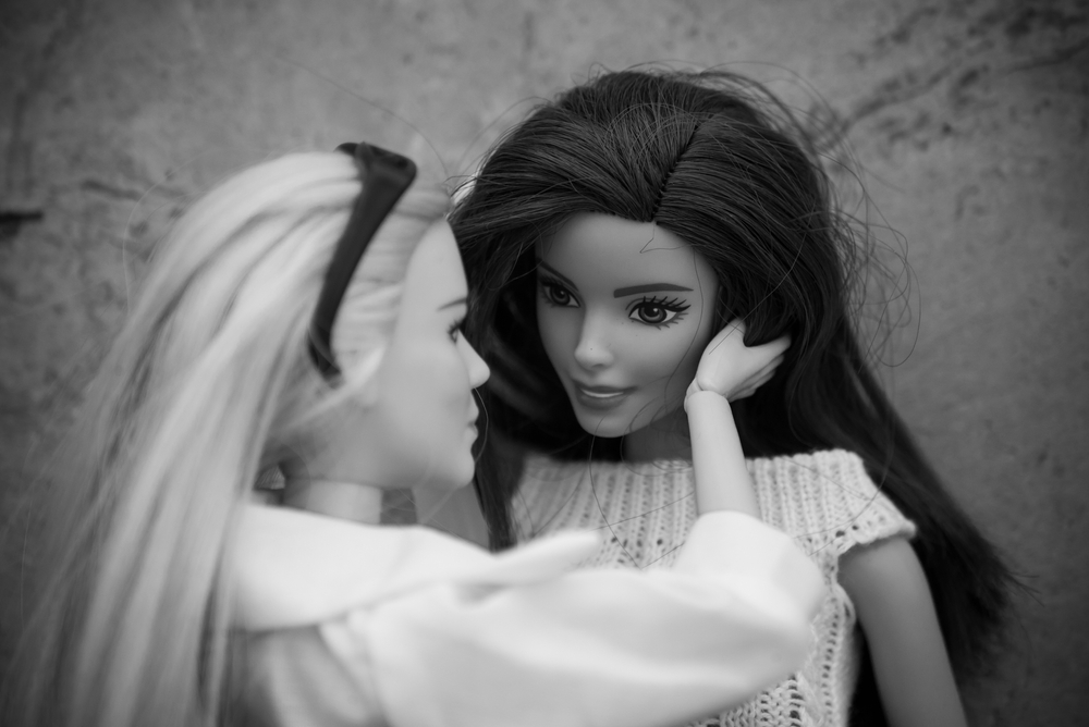 a black and white photo of two barbies engaged in a near kiss