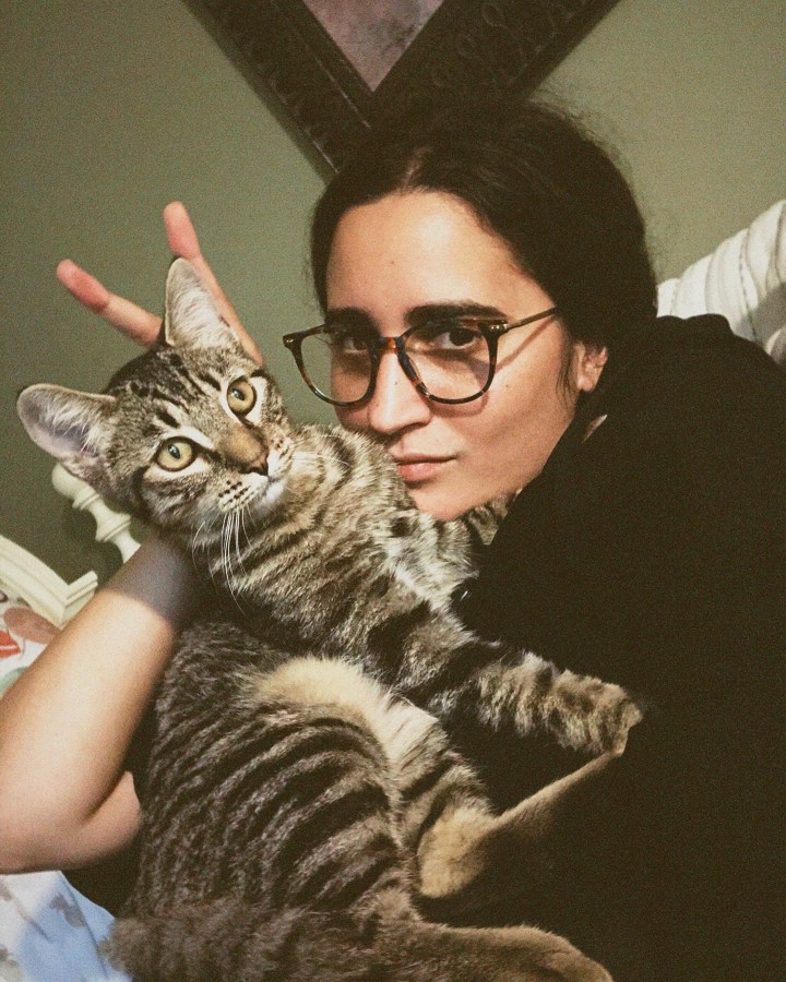 a striped cat sitting on the author Kayla Kumari Upadhyaya who is giving him bunny ears