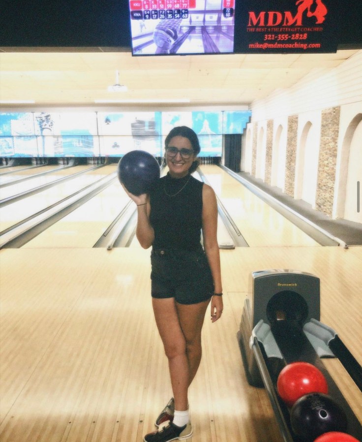 the author Kayla Kumari Upadhyaya holding a bowling ball at a bowling alley